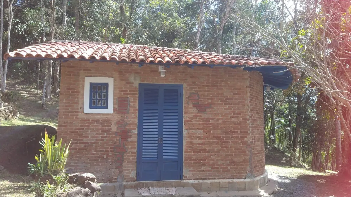 O chalezinho de tijolo com porta azul, no meio da mata