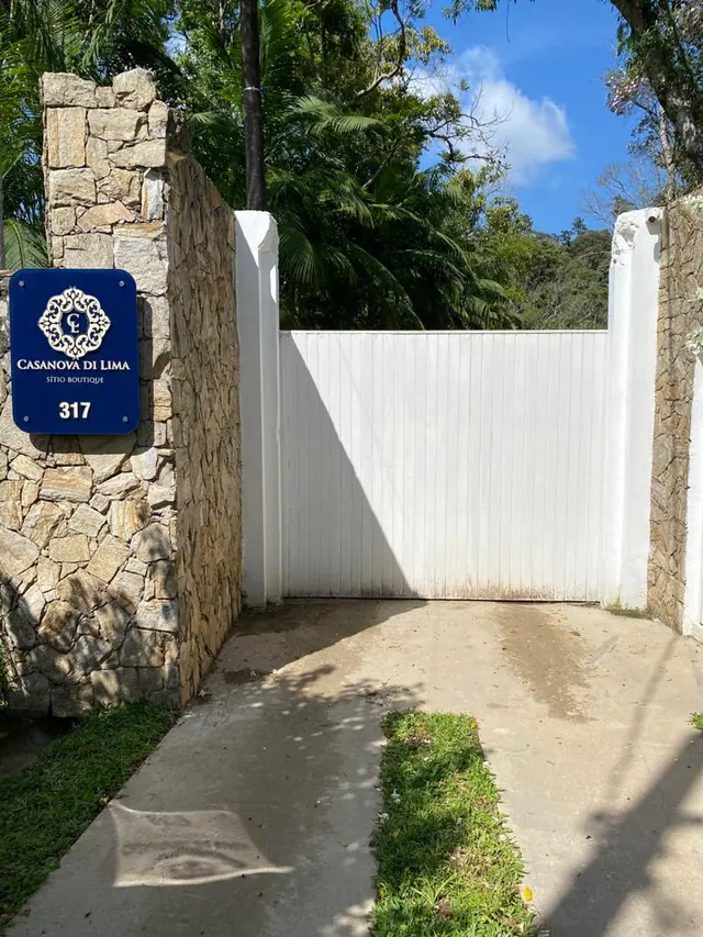 Portão de pedra do sítio, com a placa azul do brasão