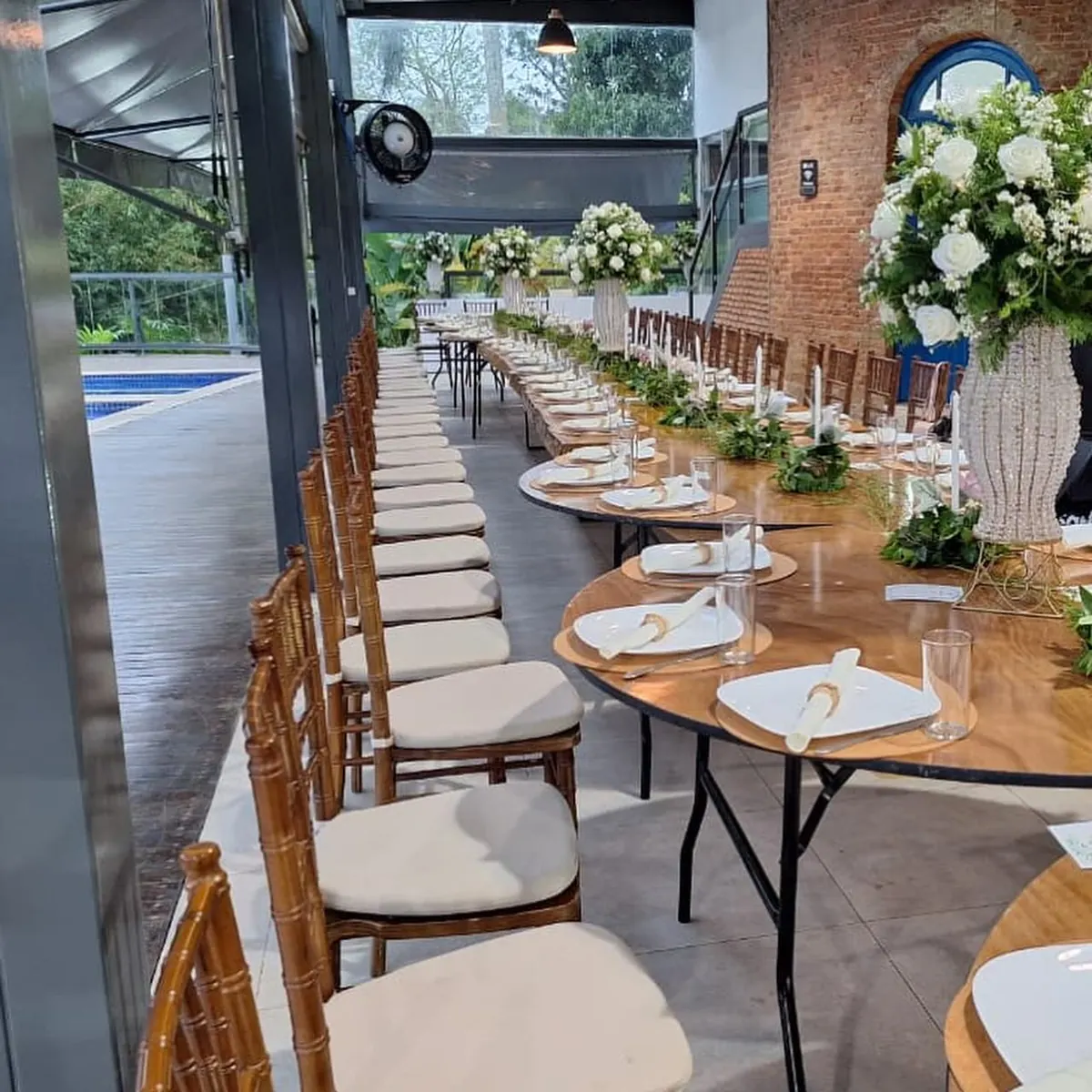 Mesa de jantar posta com arranjos de flores brancas no salão